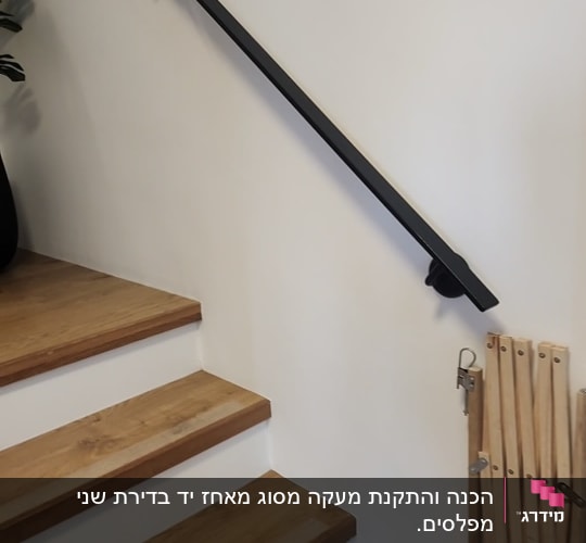 מעקה שחור על קיר לבן ליד מדרגות עץ